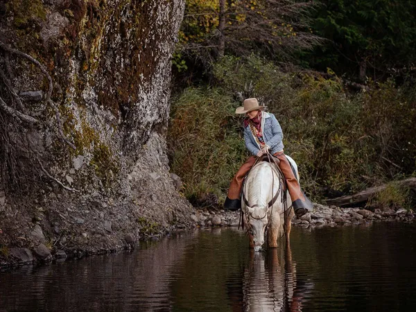 Appaloosa Horse and rider, cowgirl standing in water with their image reflecting in the water