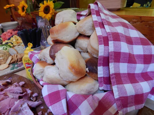 A basket of dinner rolls in a red checked cloth