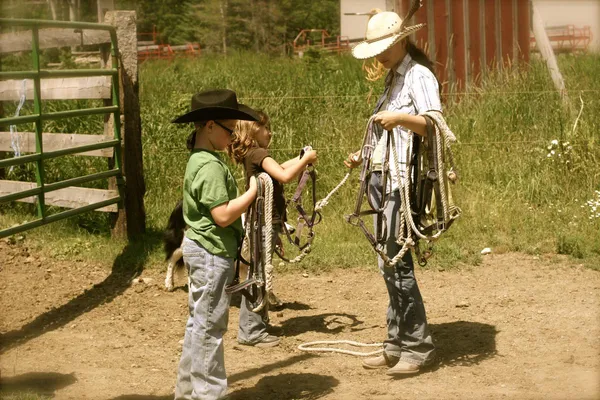 Two children practice roping with a wrangler