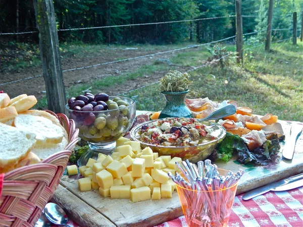 Cheese, olives, bread and salads set out on a table outdoors