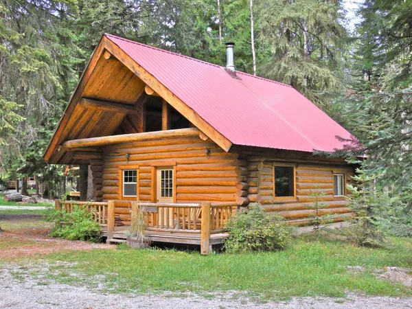 Settler log cabin with a red roof and front porch among the trees
