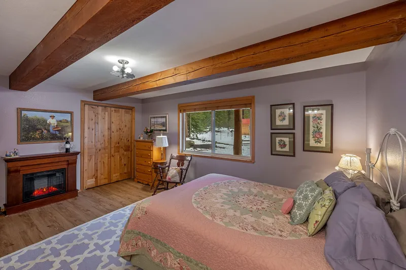 Grandma's Room, looking across the quilted bed to an electric fireplace, a rocking chair and a window onto the snow