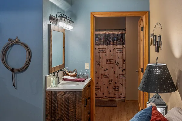 Vanity and mirror in Grandpa's Room, with a coiled rope on the blue wall and the bath beyond
