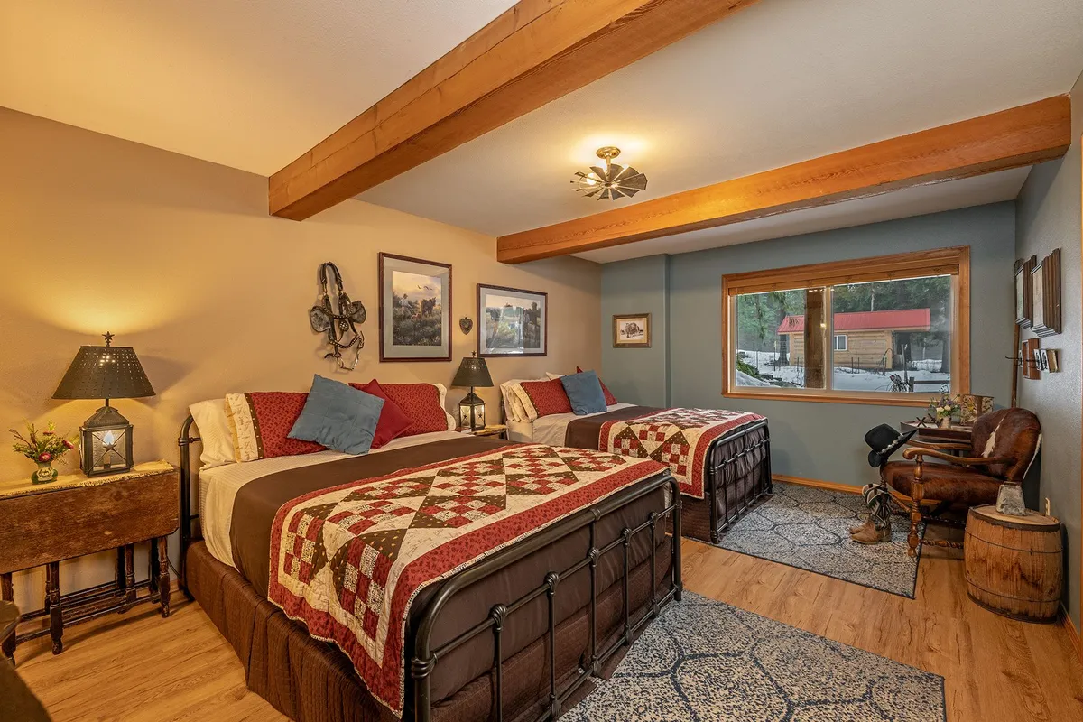 Grandpa's Room, with two iron beds in red patchwork quilts, a leather armchair and a wide window