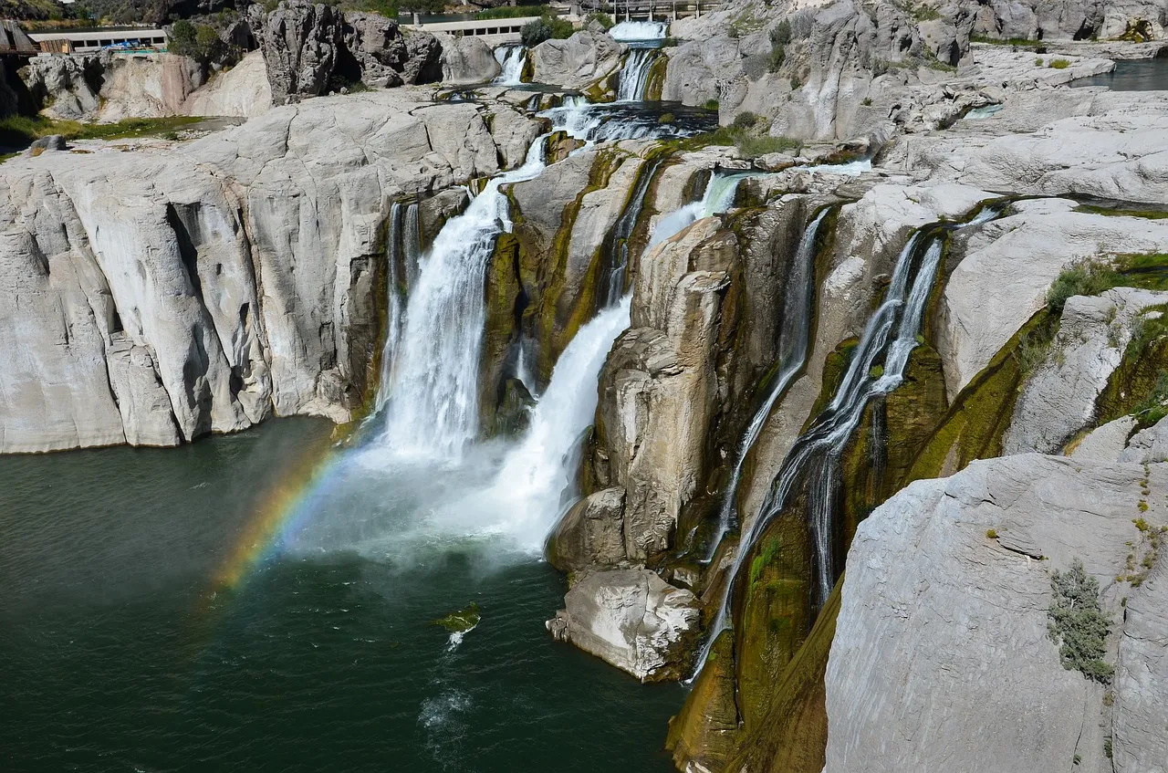 White rocky cliffs with many waterfalls and rainbow in the water spray