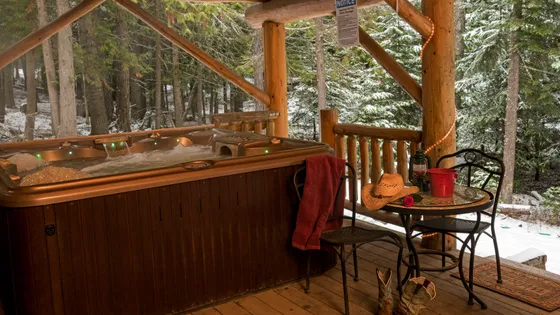 The covered outdoor hot tub on the lodge deck, with a small table and chairs beside it