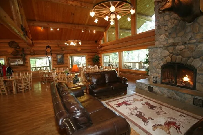 Lodge great room with warm fire burning in river rock fire place
