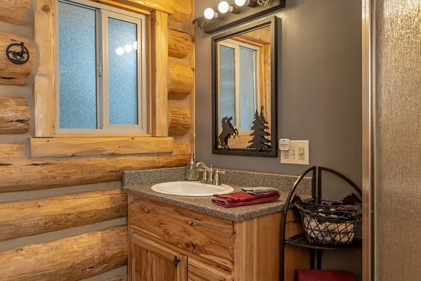 Meadow View Cabin bathroom, with a wood vanity, a log wall and a stack of towels