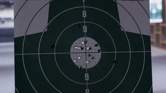 A paper bullseye target with a cluster of holes near the center