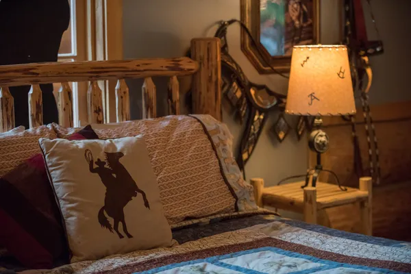 Log bed with pillows and quilt in John Wayne themed room lamp in the background