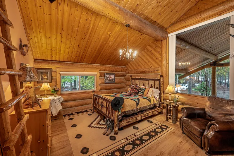 Log bed with a Southwestern quilt in the Nez Perce room, beside a leather armchair and a large window
