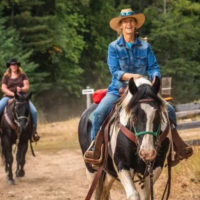 woman on gypsy vanner horse riding with other people on horseback behind her