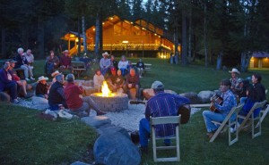 people sitting around a campfire listening to musicians play cowboy music