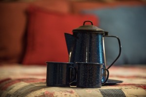 blue camp cups and coffee pot on quilt