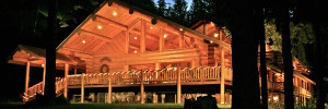 large log Lodge lit by lights at night