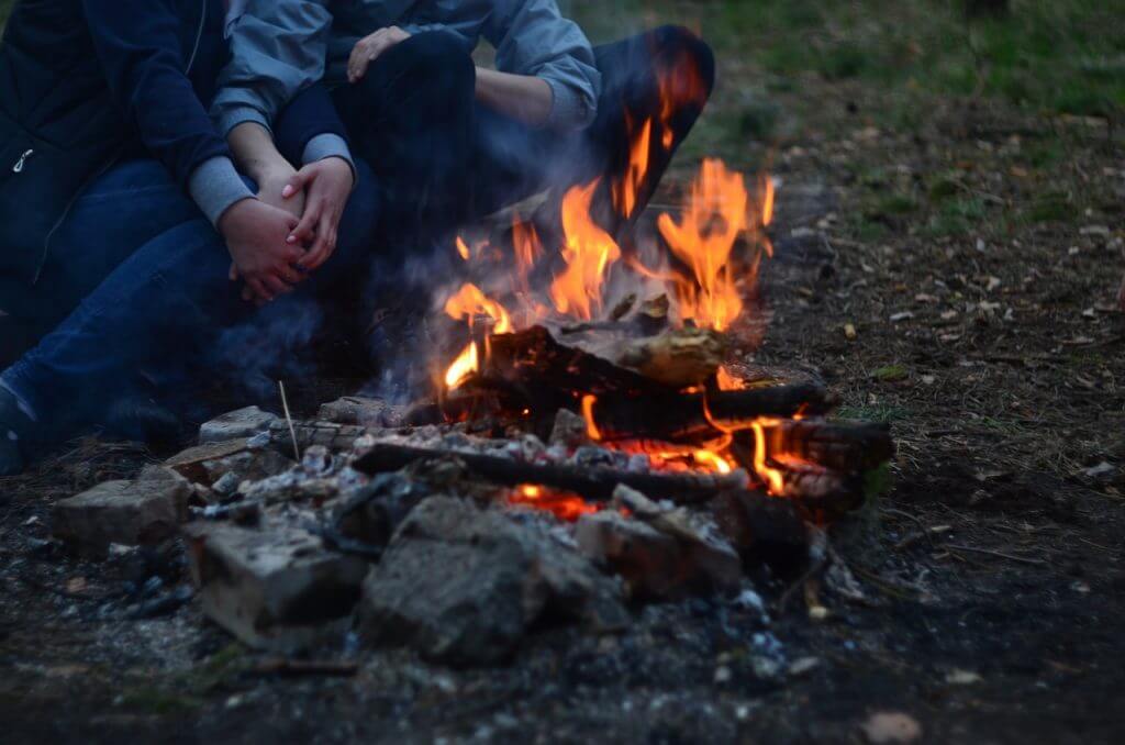 Fall travel campfire with couple holding hands