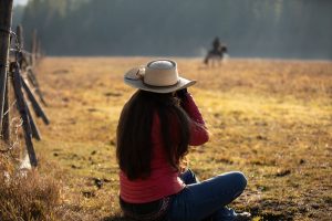 Photographer sitting on the ground taking a photo of a rider in the field