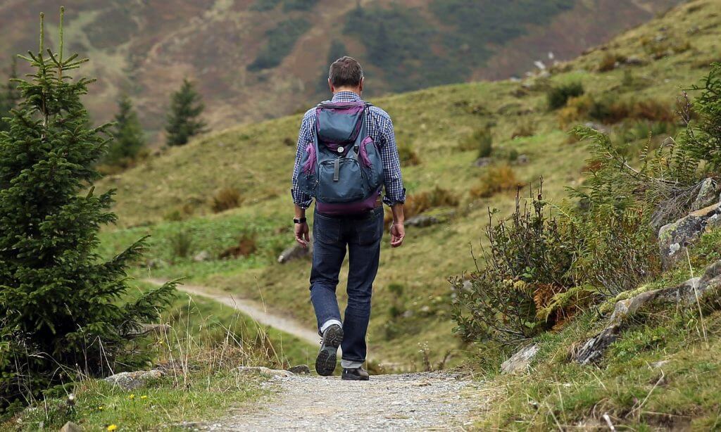 Man facing away, hiking on a trail